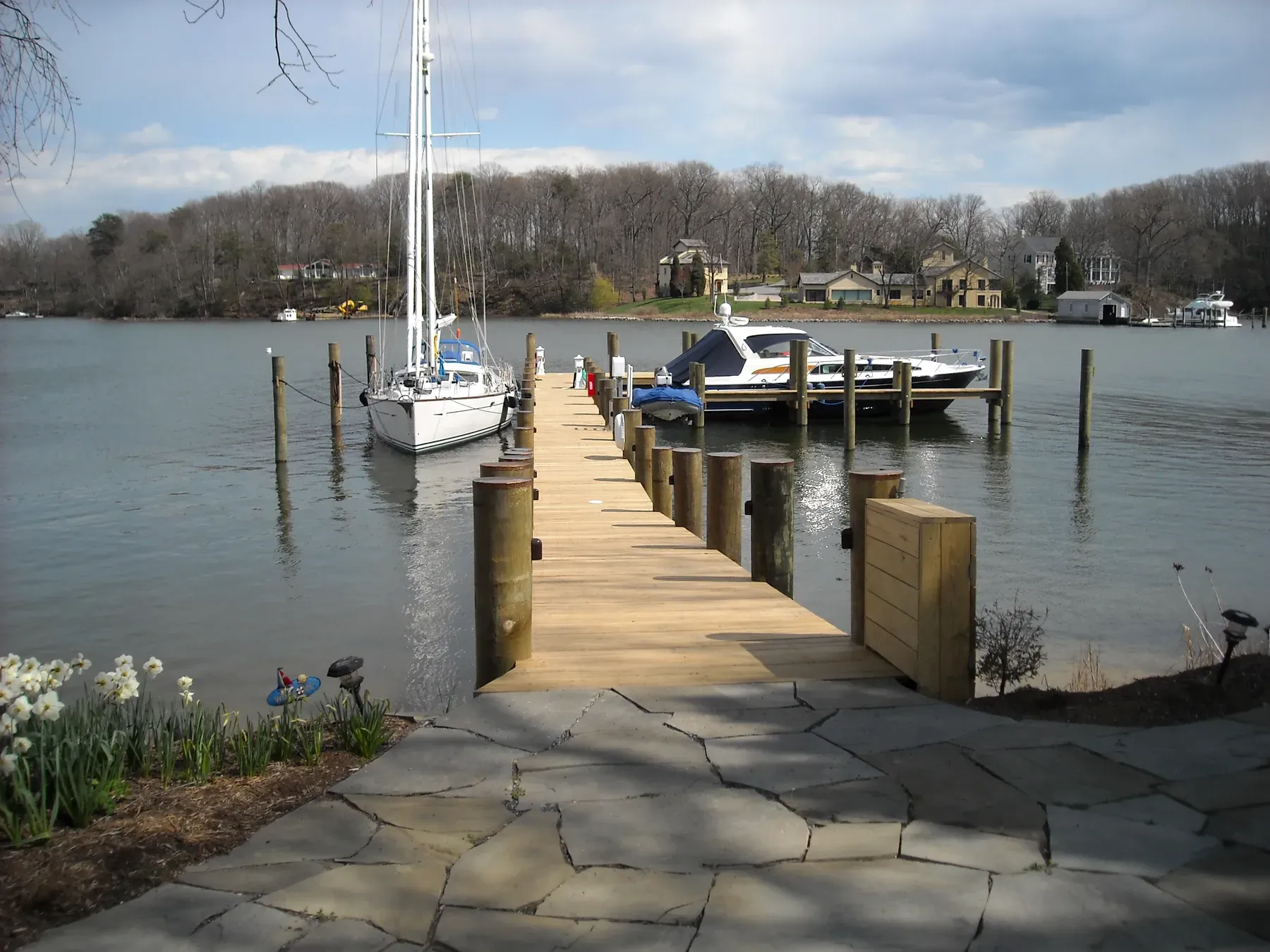 New pier running from a flagstone landing toward a moored sailboat